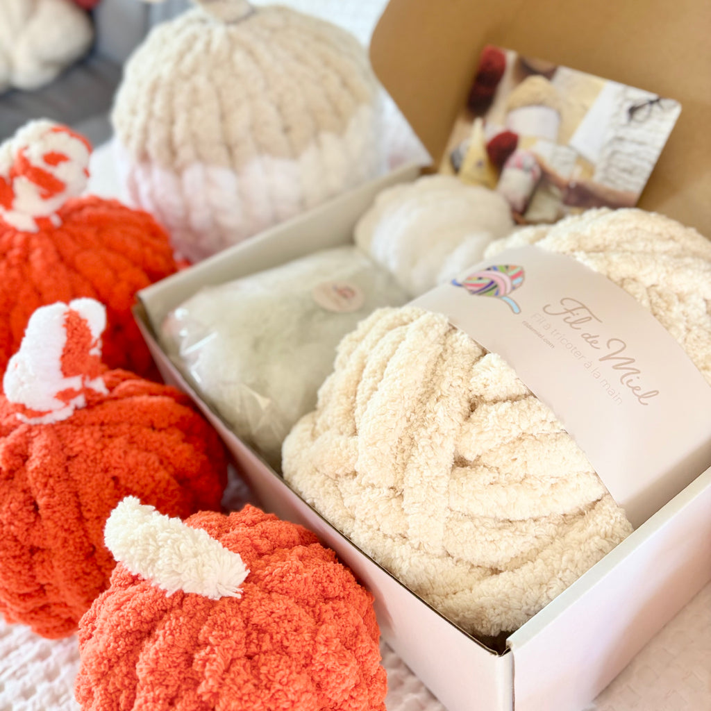 Kit Citrouille Créatif – Spécial Halloween: pelotes de fil moelleux crème et orange dans une boîte, ambiance artisanat.
