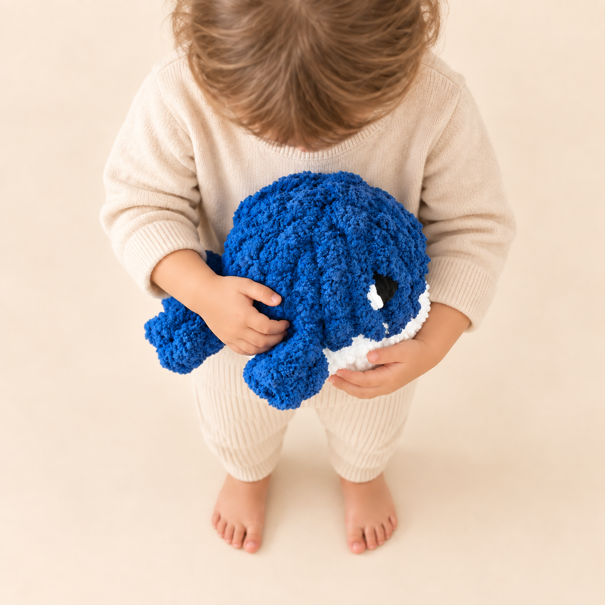 Enfant debout tenant Néo la baleine bleue en fil chenille XXL – Fil de Miel