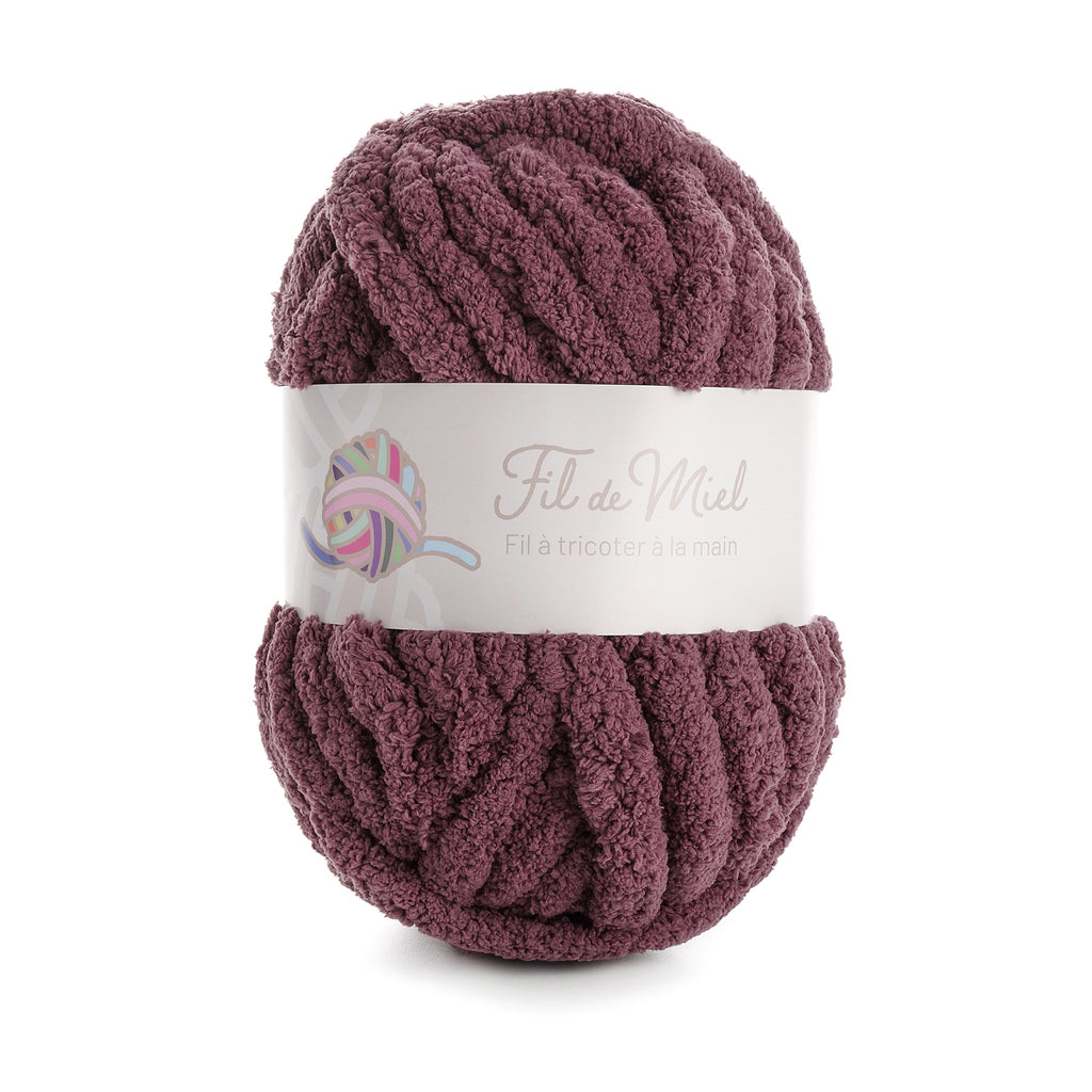 Pelote de laine marron chocolat, texture épaisse et bouclée sur fond blanc, étiquette “Fil de Miel” visible.