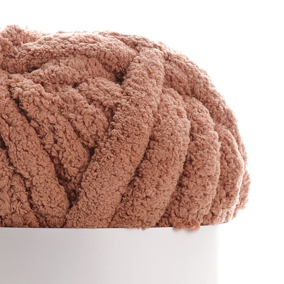 Texte alternatif : Écharpe ou couverture moelleuse couleur caramel en tricot bouclé reposant sur un socle blanc. Mot clé principal: Caramel.