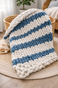 Couverture bébé au crochet sans aiguilles, gris clair et bleu, posée sur un tapis rond dans une chambre douillete.